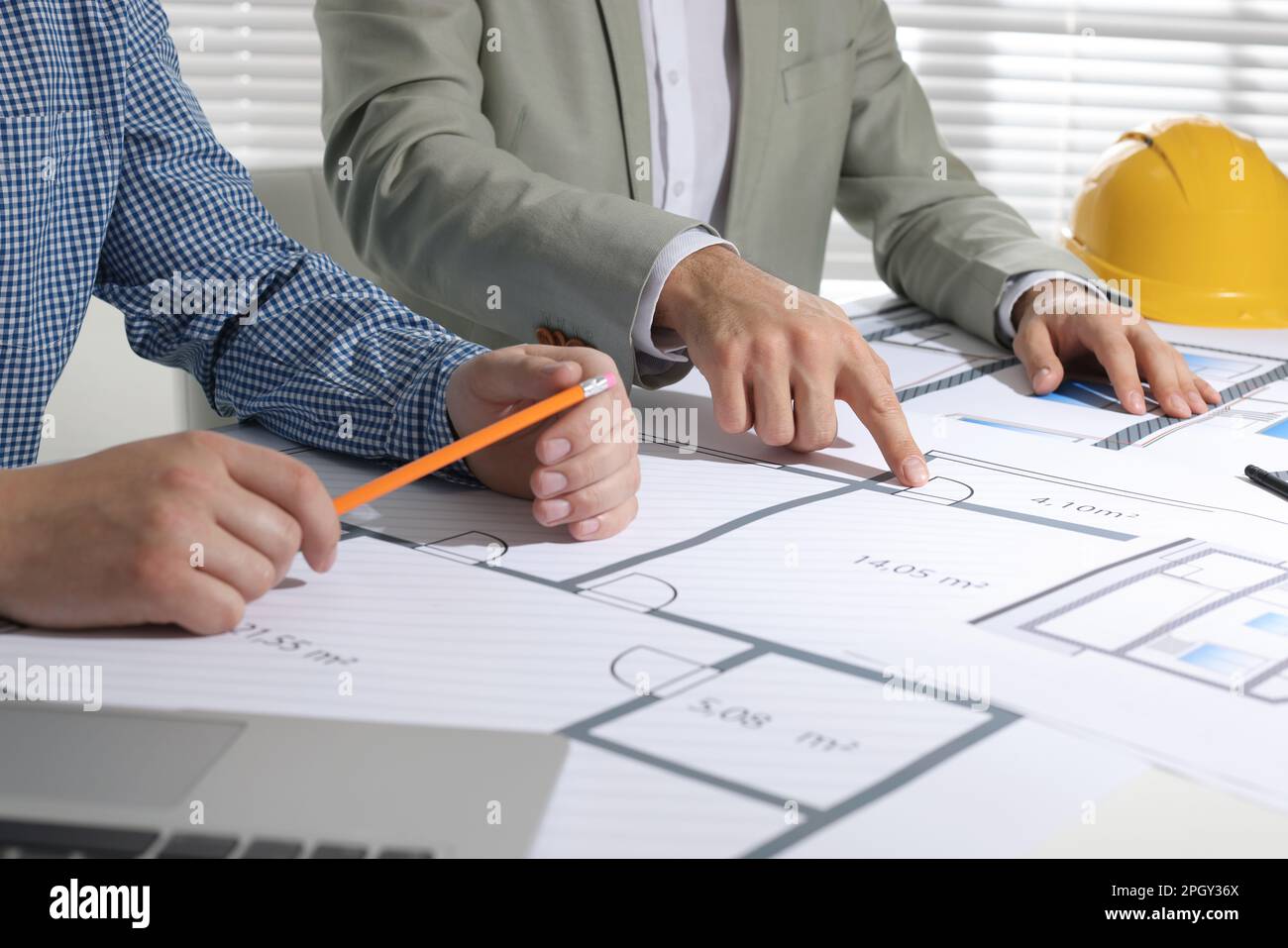 Architects working with construction drawings at table in office, closeup Stock Photo