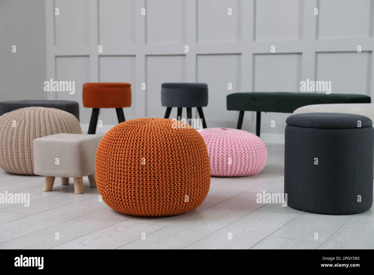 Different stylish poufs and ottomans in room Stock Photo - Alamy