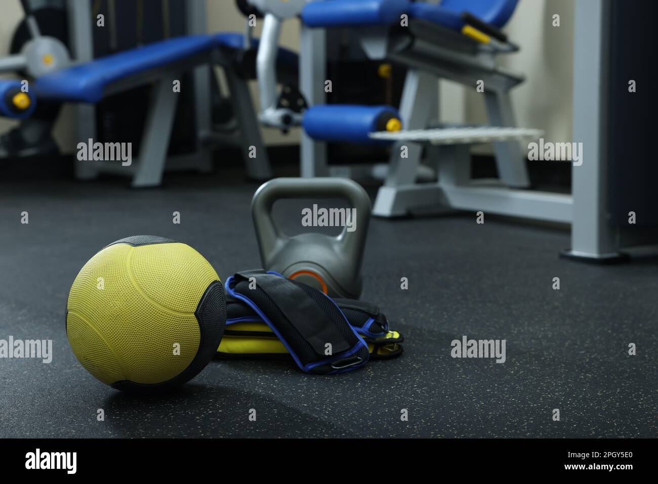 Yellow medicine ball, kettlebell and ankle weights on floor in gym
