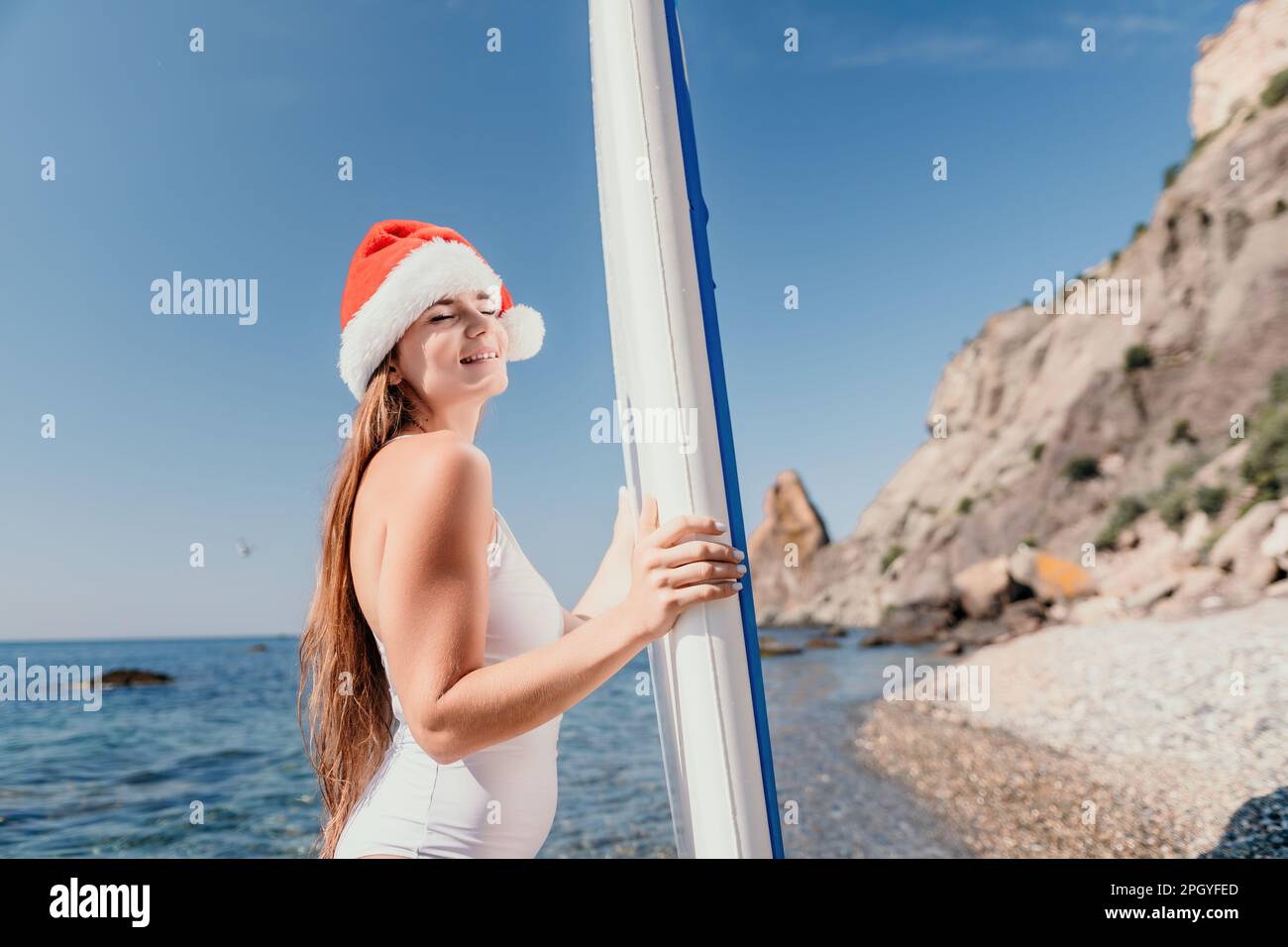 Woman sea sup. Close up portrait of happy young caucasian woman with long hair in Santa hat looking at camera and smiling. Cute woman portrait in a Stock Photo