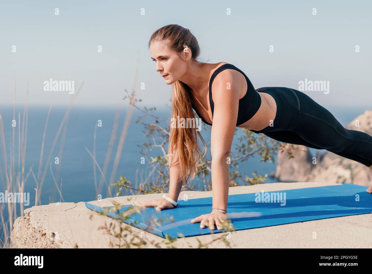 Fitness woman sea. Outdoor workout on yoga mat roller in park near to ocean beach. Female fitness pilates yoga routine concept. Healthy lifestyle Stock Photo