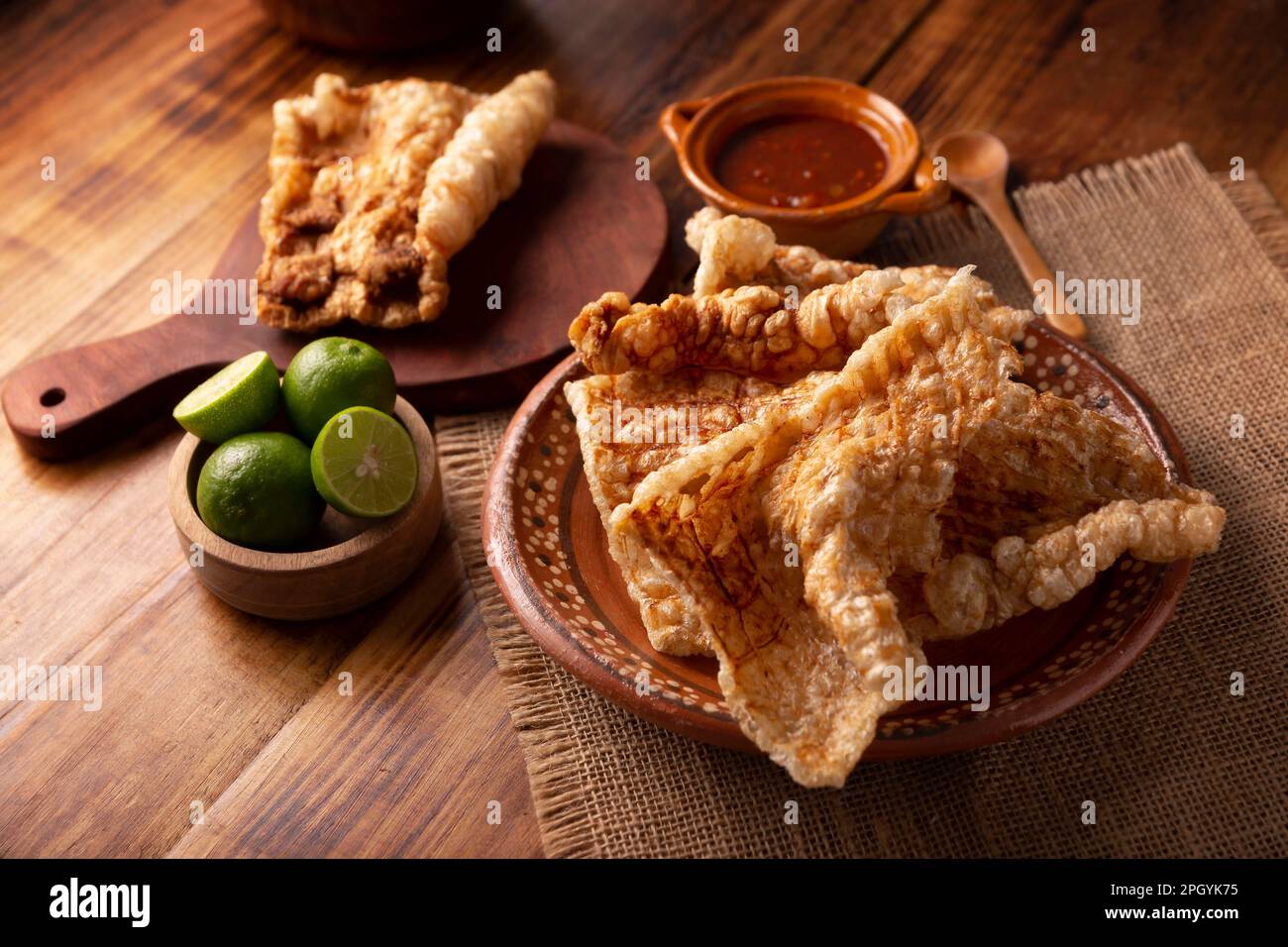 Chicharron. Crispy Fried pork rind, are pieces of aired and fried pork skin, traditional Mexican ingredient or snack served with lime juice and red ho Stock Photo