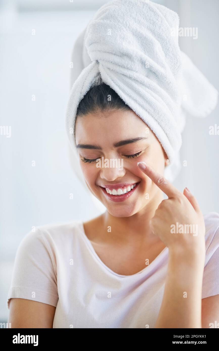 Nourished skin glows beautifully. a beautiful young woman applying