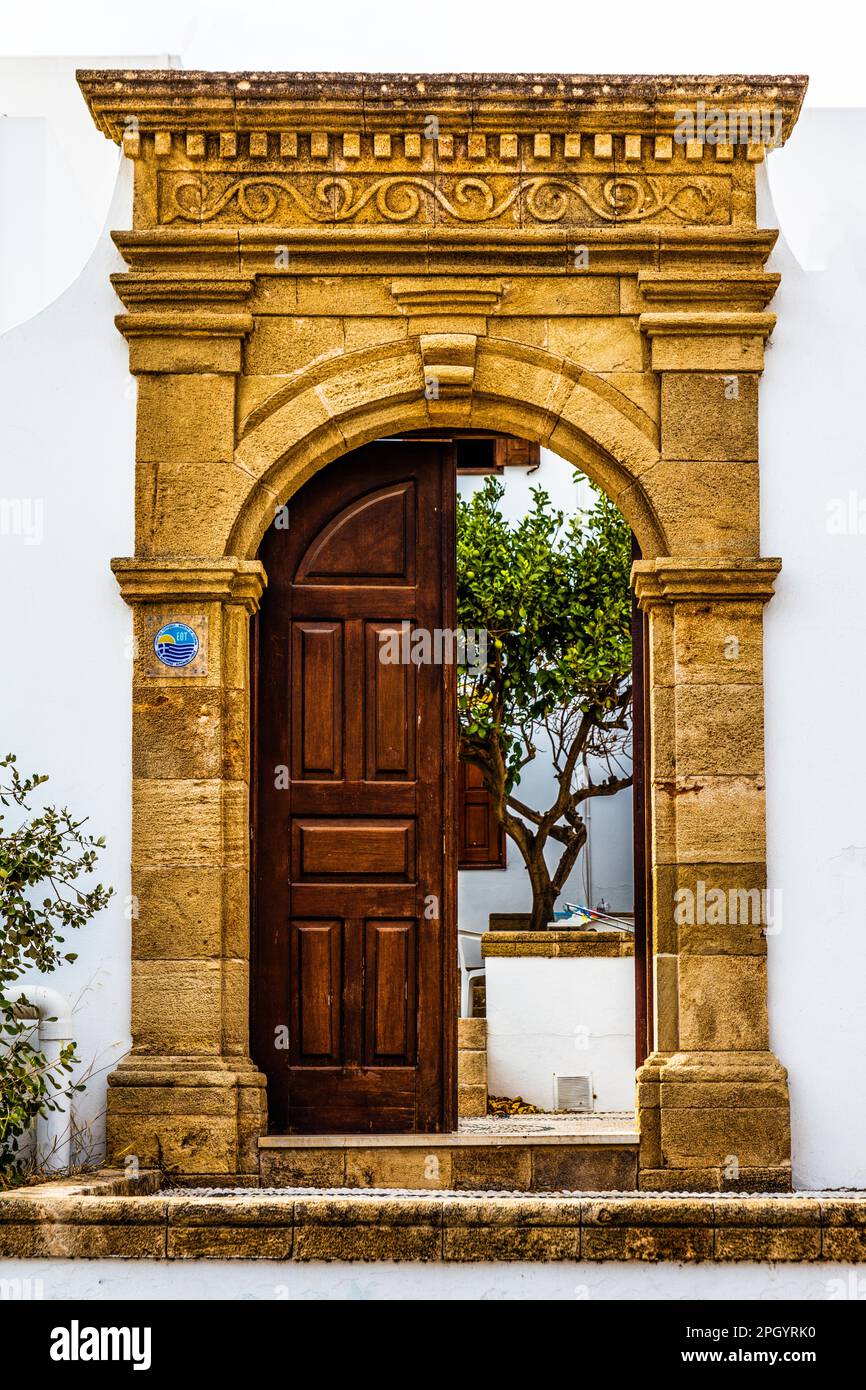 Old wooden doors with pebble mosaics on the floor, winding streets with white houses, Lindos, Rhodes, Greece Stock Photo