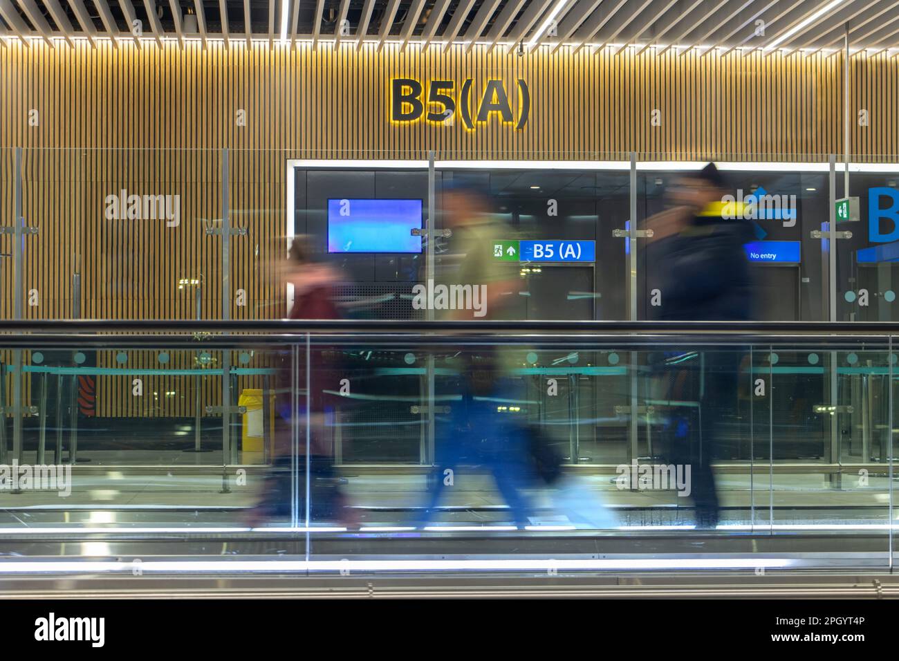 Passengers move on a moving walkway in the airport terminal Stock Photo