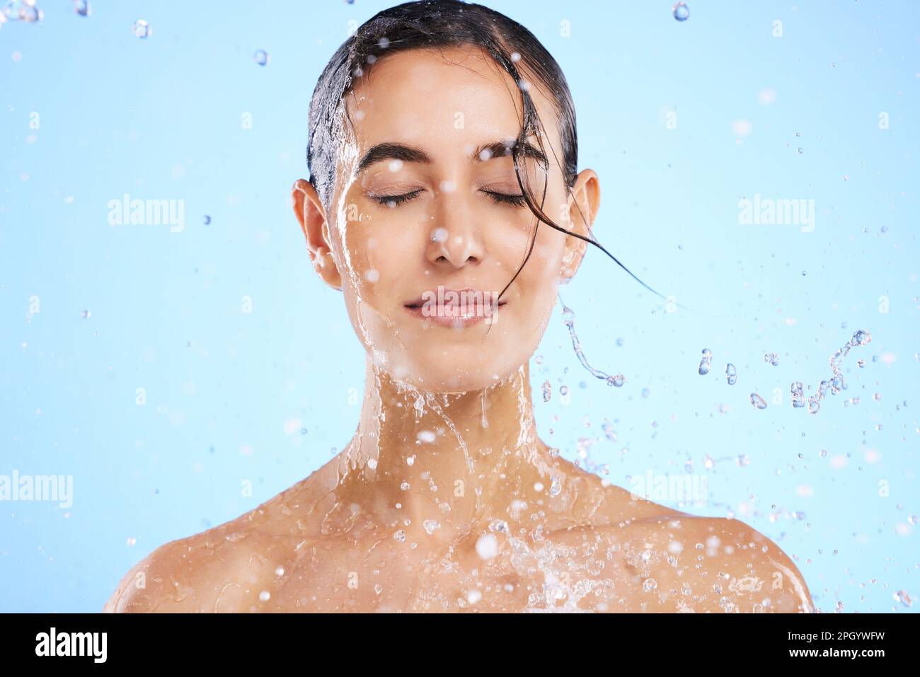 Water splash, beauty and skincare with a woman in studio on a blue