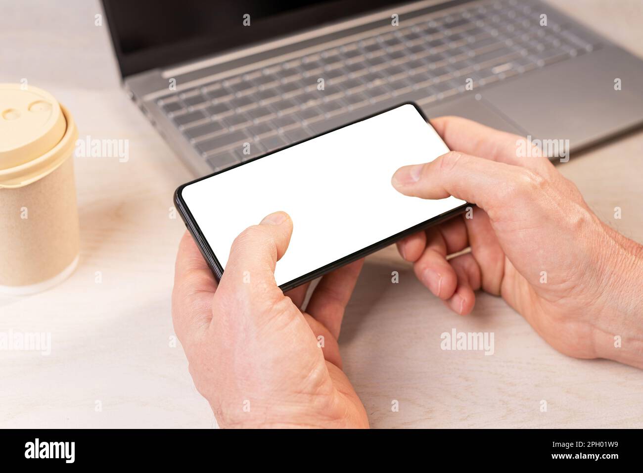 Thumb fingers on smartphone screen on mobile phone mockup, playing game at workplace, office desk. Stock Photo