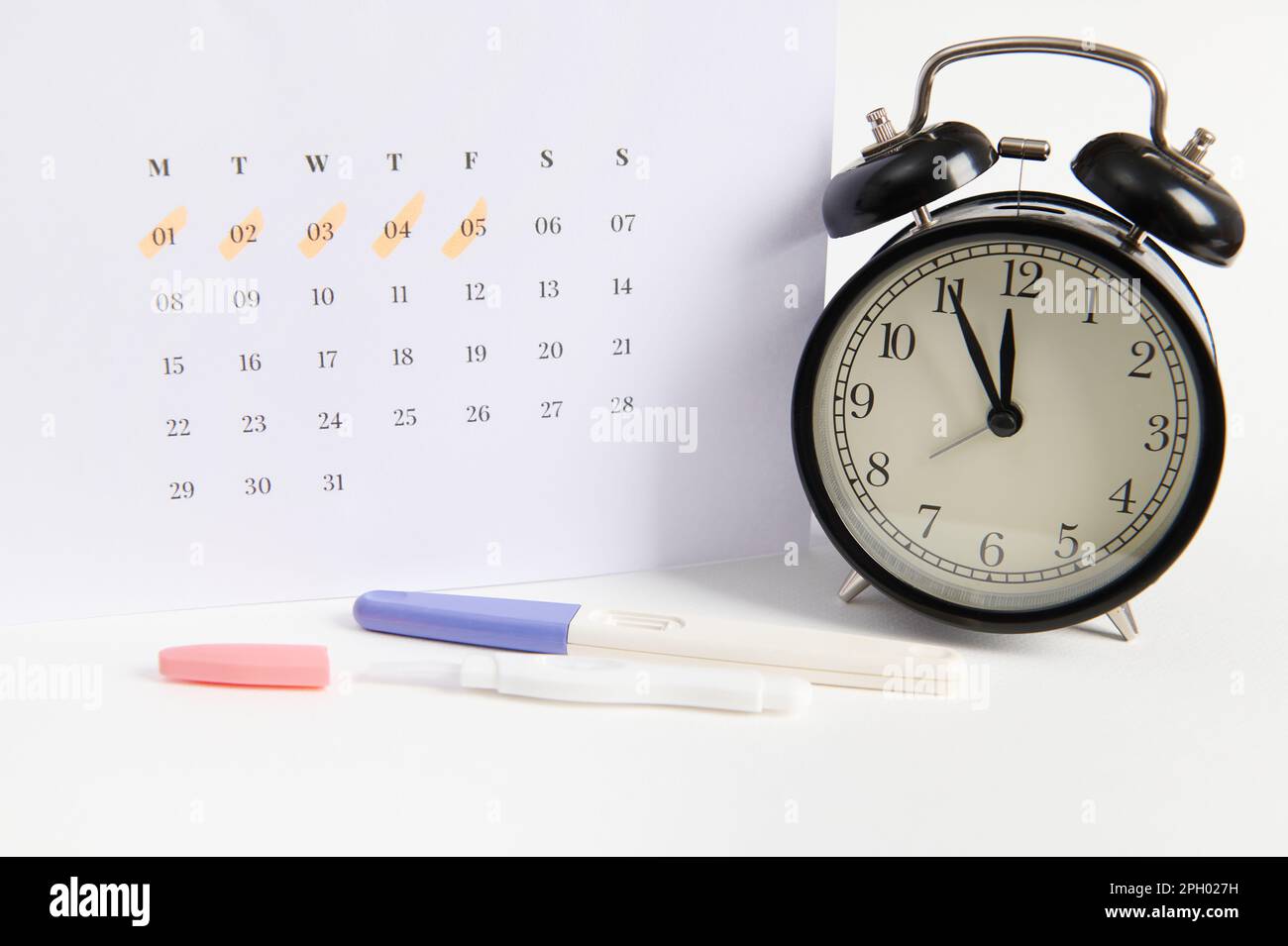 Positive inkjet pregnancy test, black retro alarm clock and white