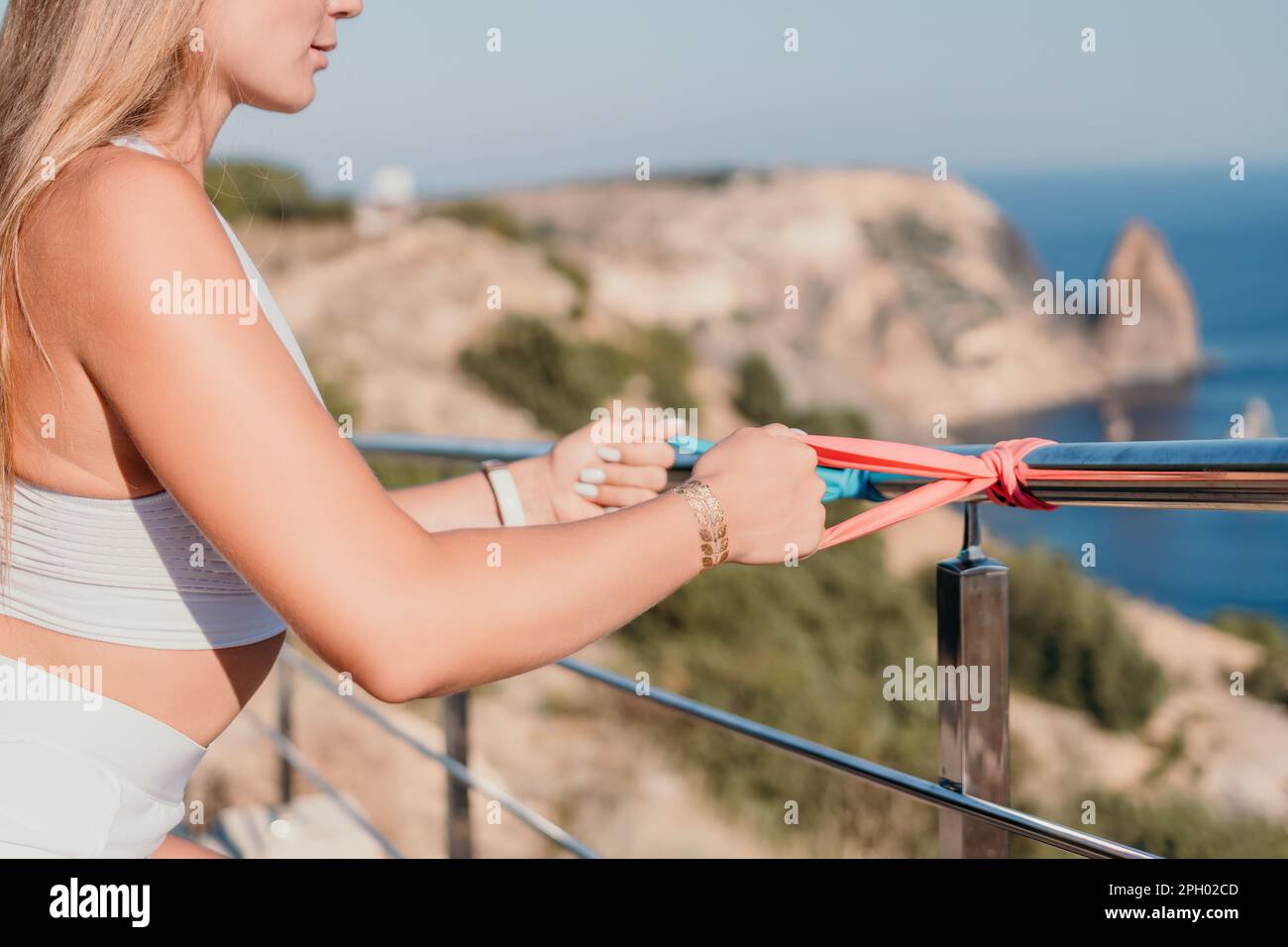 Fitness woman sea. Outdoor workout with fitness rubber bands in park over beach. Female fitness yoga routine concept. Healthy lifestyle. Happy fit Stock Photo