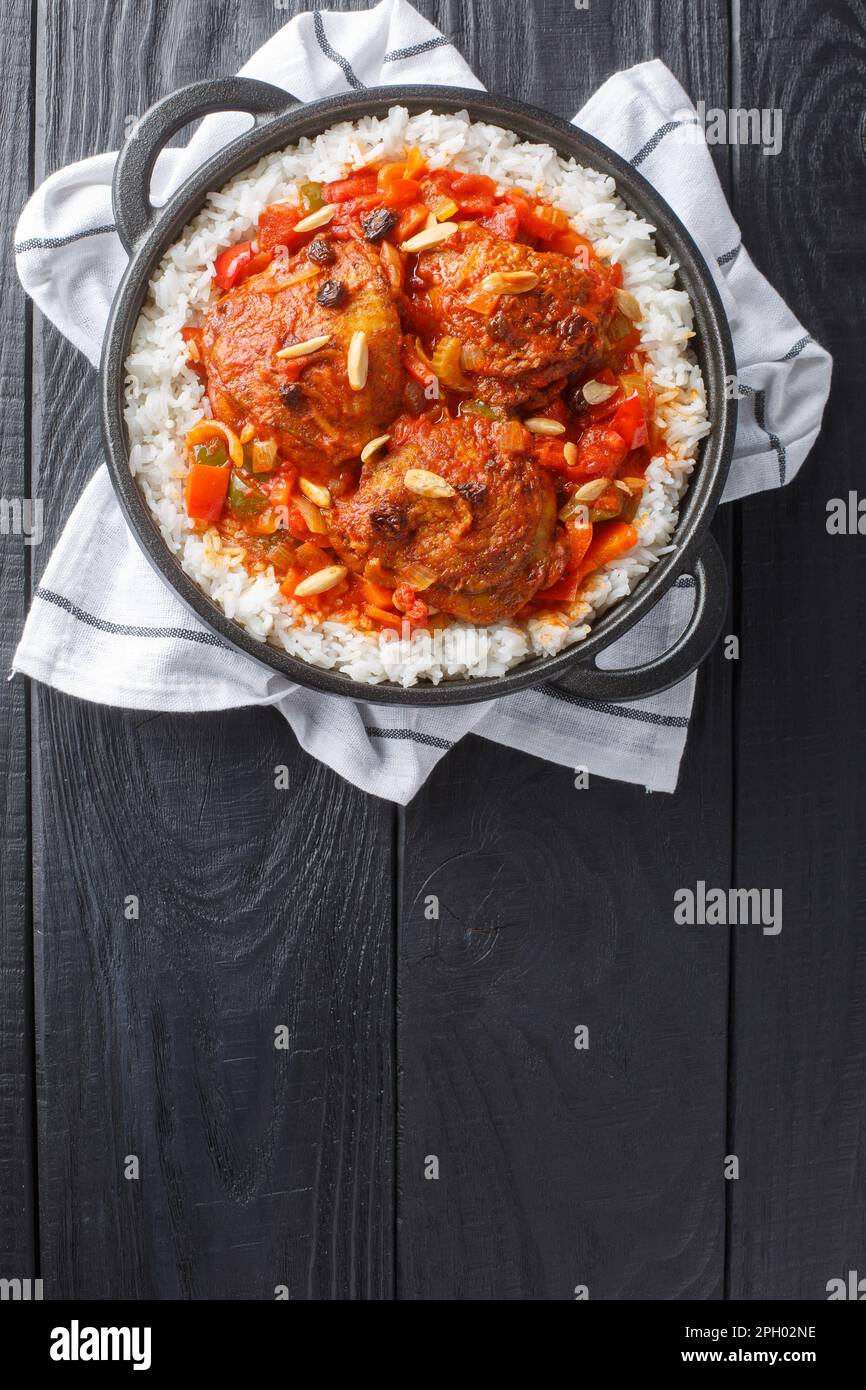 Country Captain chicken fried in bacon fat, then stewed with tomatoes fragrant with curry and pepper and served over white rice closeup on the pan on Stock Photo