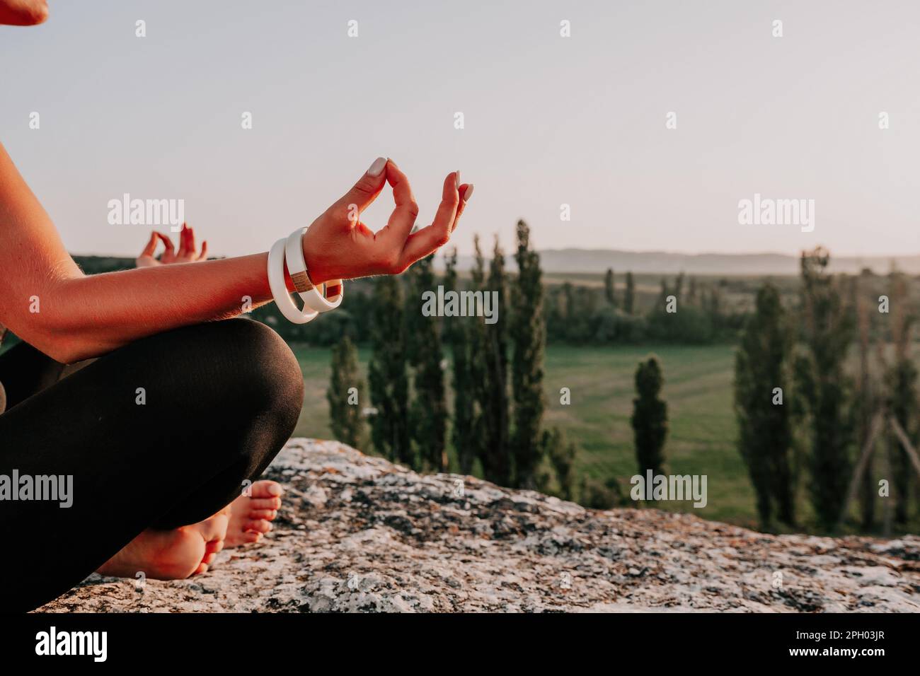 Fitness woman. Well looking middle aged woman with long hair, fitness instructor in leggings and tops doing stretching and pilates on the rock near Stock Photo