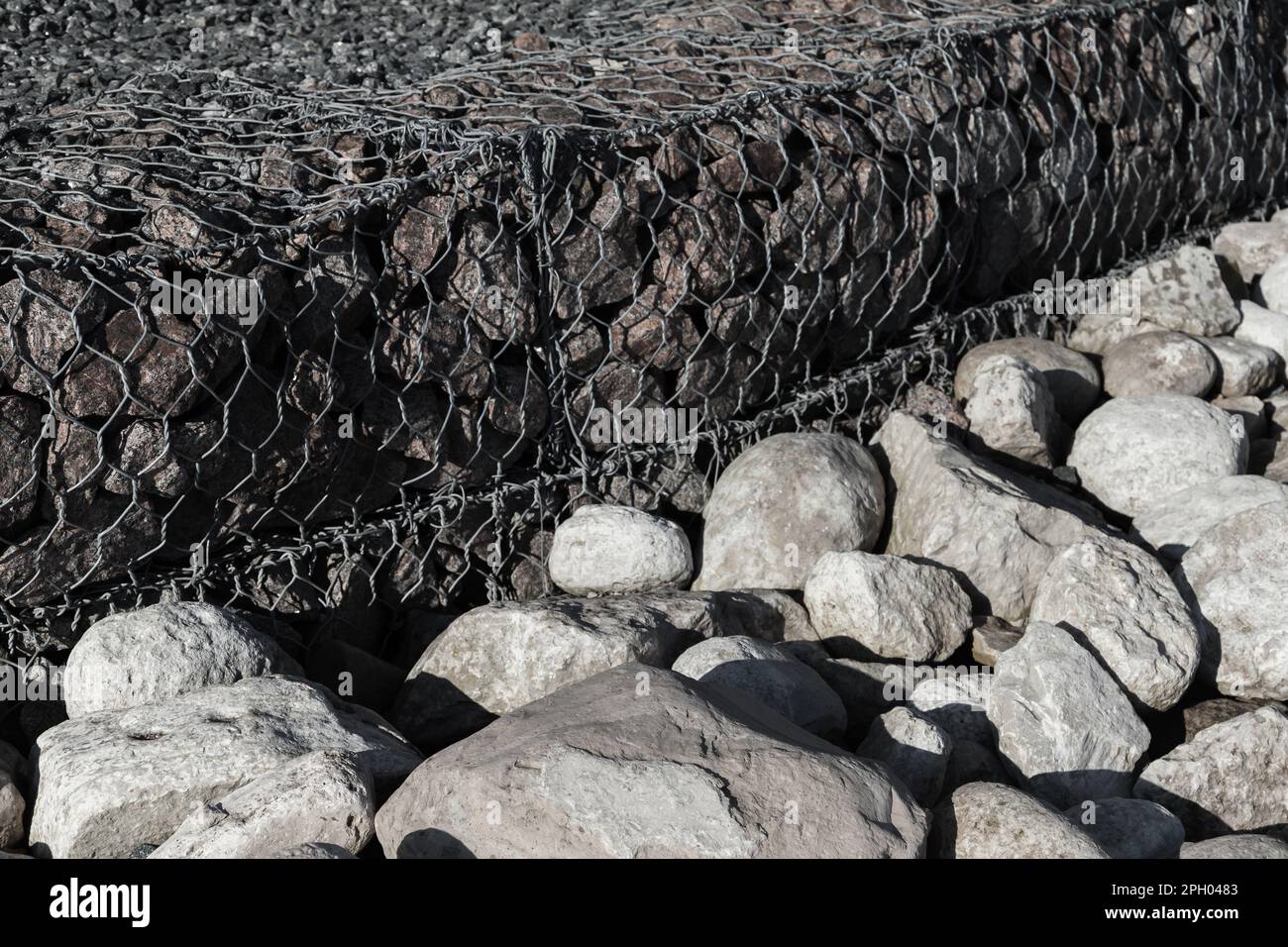 Gabion and rough stones at the roadside. Cage boxes filled with rocks