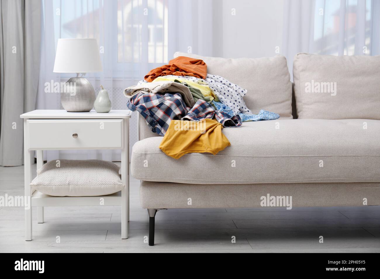 Messy pile of dirty clothes on sofa in living room. Tidying up method