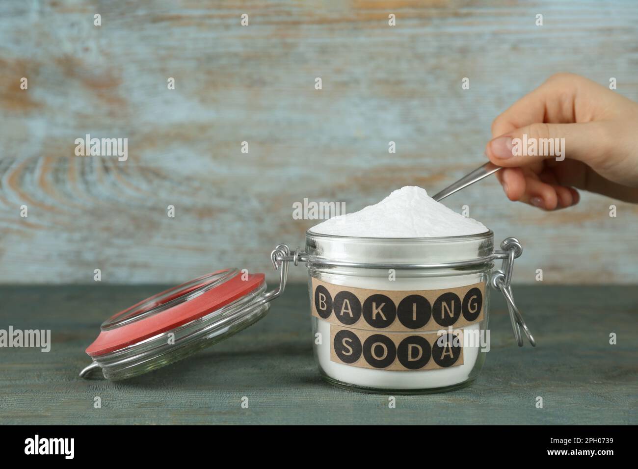 Woman taking baking soda with spoon from jar at light blue wooden table, closeup Stock Photo Alamy