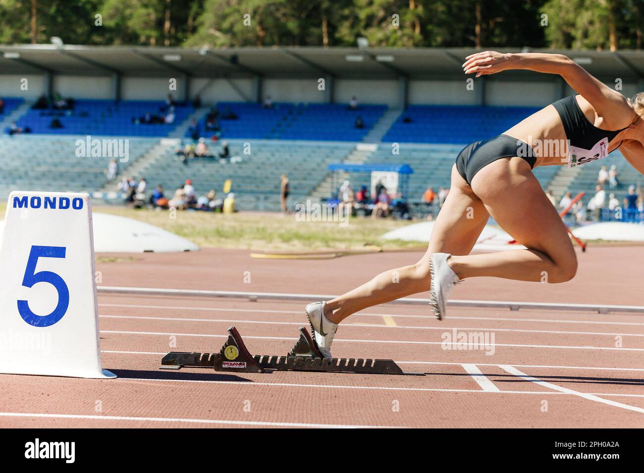 female sprinter running from starting blocks in athletics, Nike spikes shoes and Mondo lane