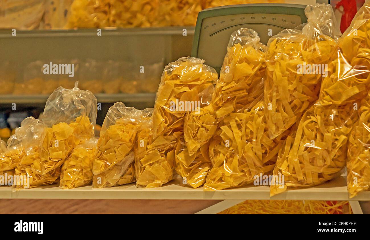 Pile of homemade raw dry pasta in plastic bags sold from market stall