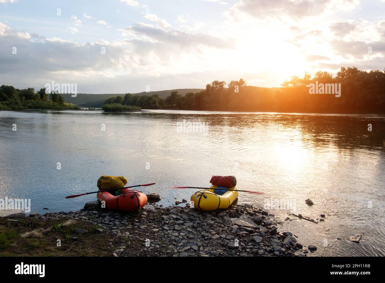 Orange and yellow packrafts rubber boats with padles on a sunrise Dnister river. Packrafting background. Active lifestile concept Stock Photo