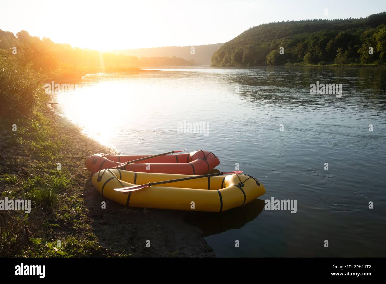 Orange and yellow packrafts rubber boats with padles on a sunrise river. Packrafting. Active lifestile concept Stock Photo