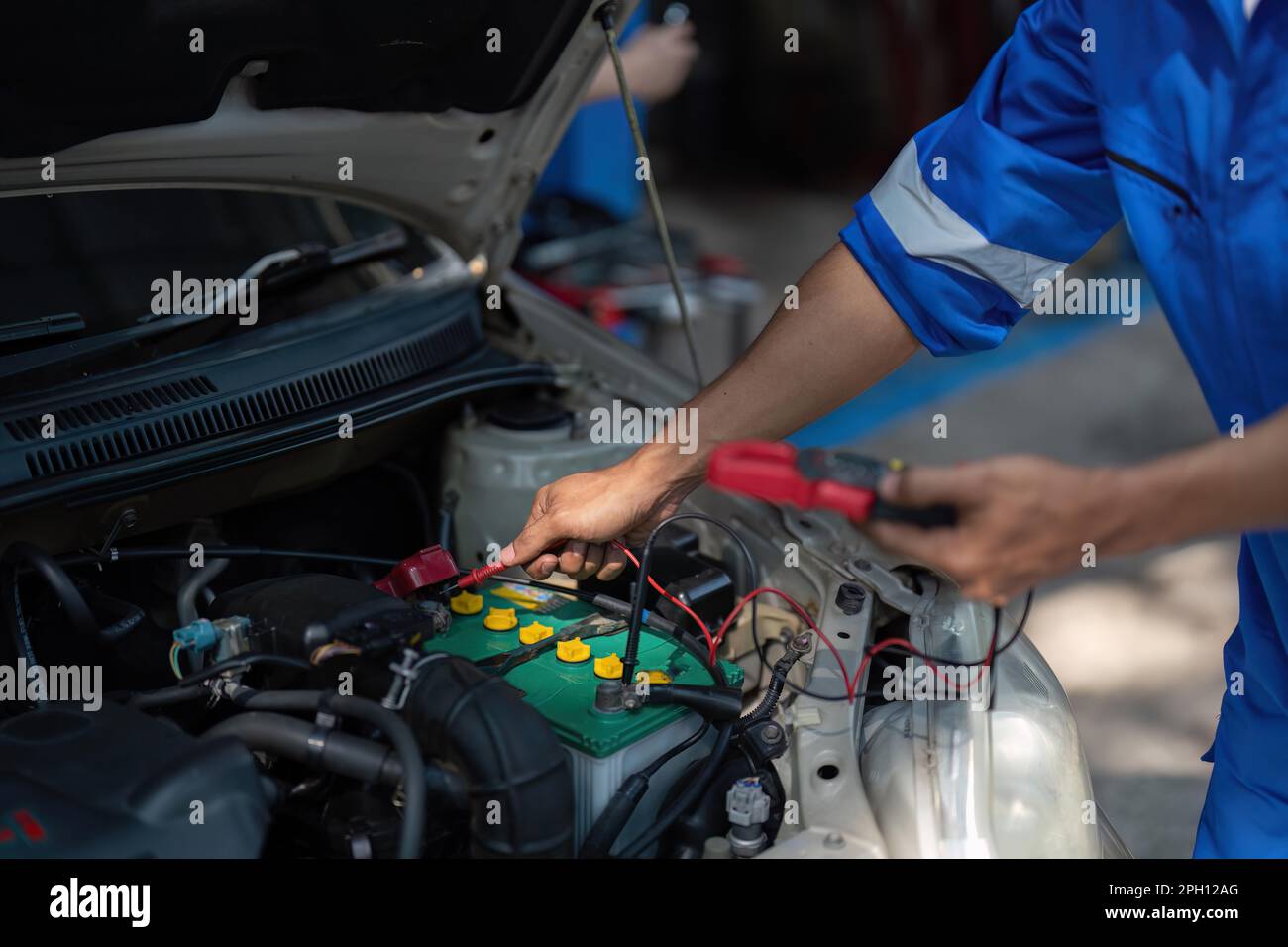 Close up technician uses multimeter voltmeter to check voltage level in car battery. Service and