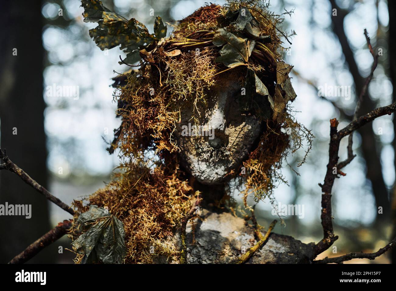 Creepy witch statue art object on forest background made of mud plaster