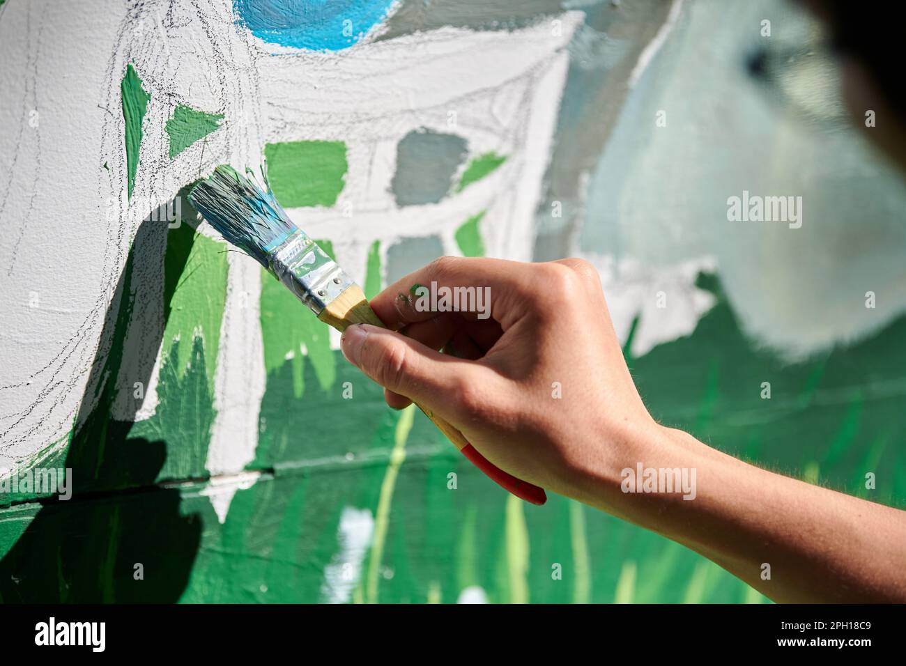 Girl artist hand holds paint brush and draws green nature landscape on