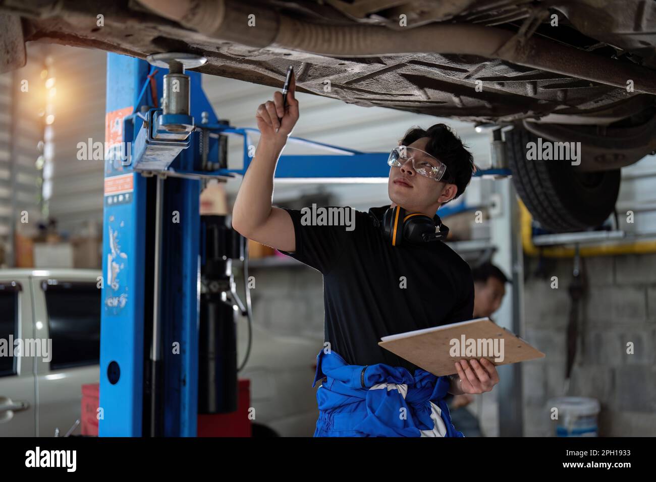 Vehicle service maintenance asian man checking under car condition in