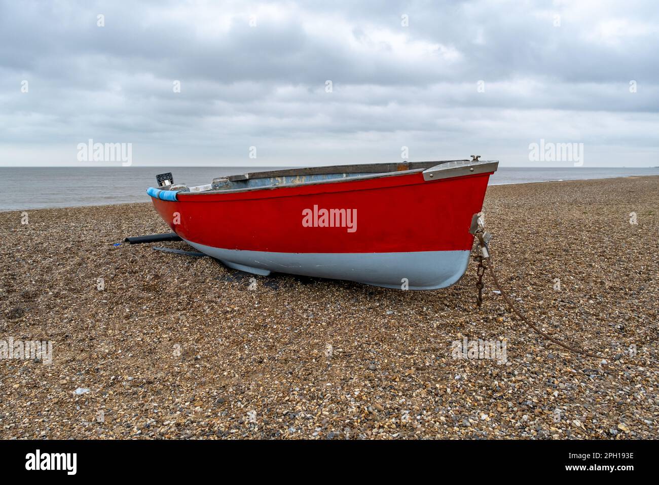Isolated wooden fishing boat on the stony beach in Dunwich on the Suffolk coast Stock Photo