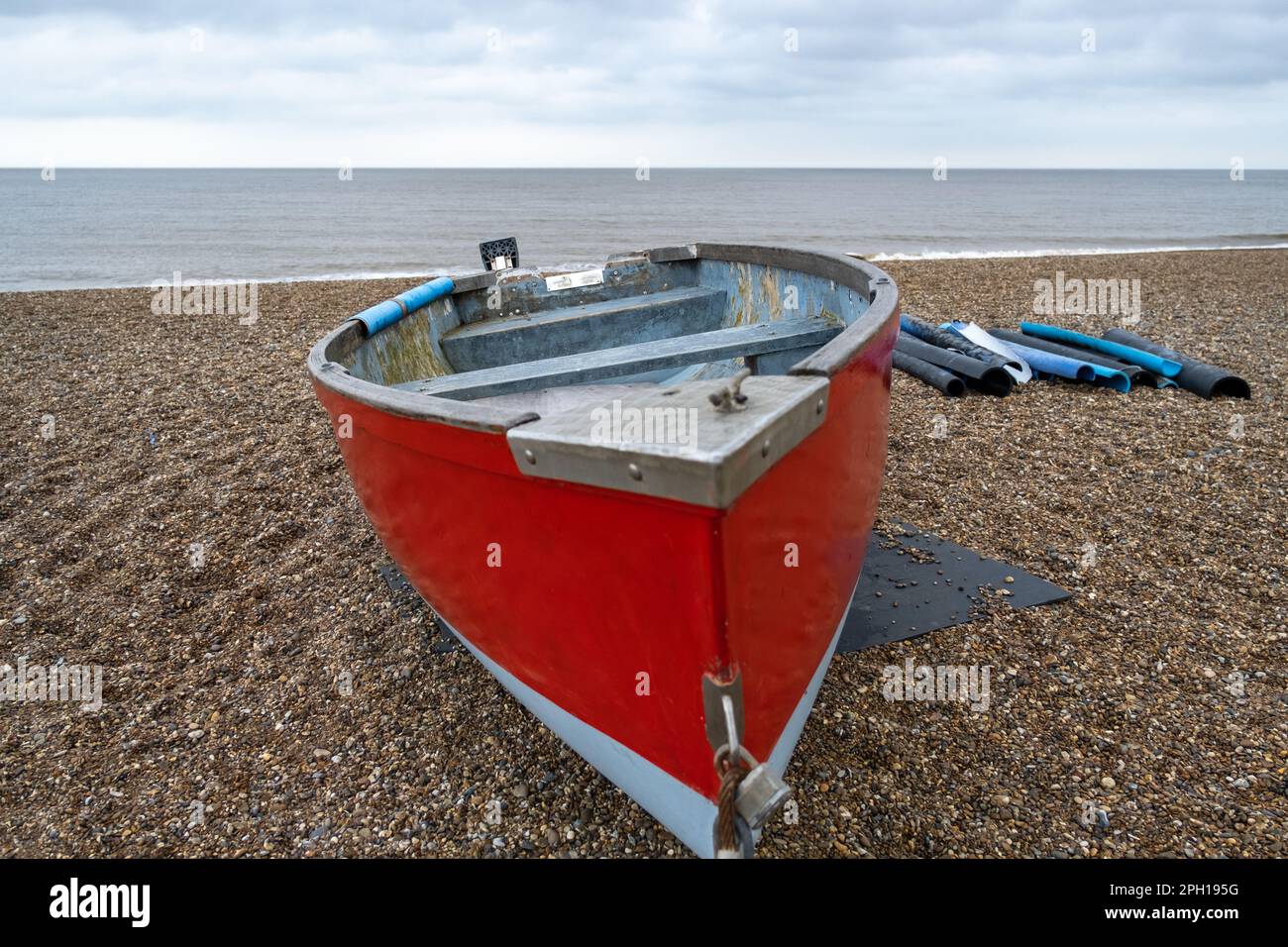 Front on view of a red fishing boat on the stony beach of Dunwich on the Suffolk coast Stock Photo