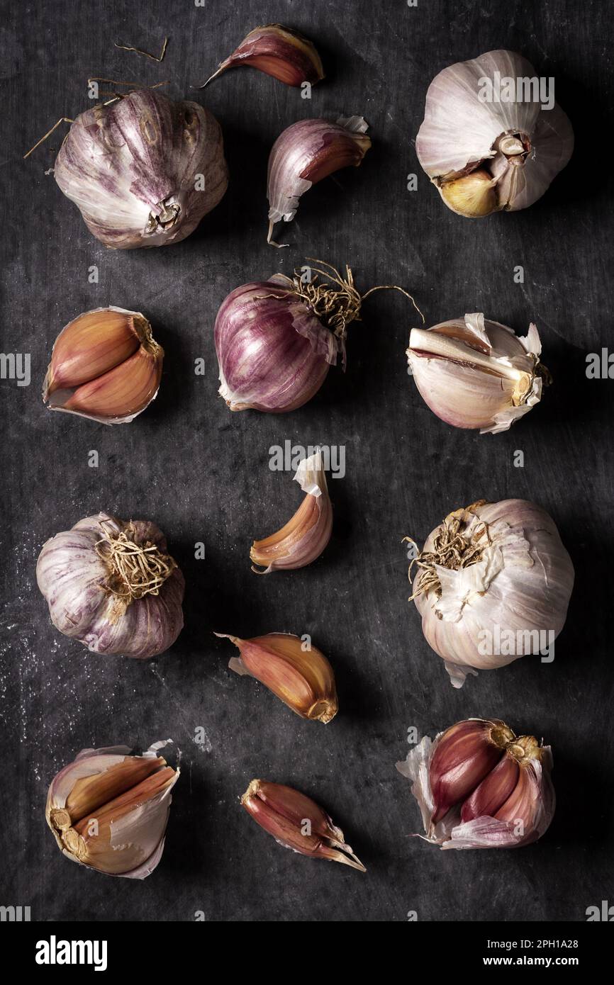 Fresh garlic bulbs and cloves grouped on black background. Flat lay ...