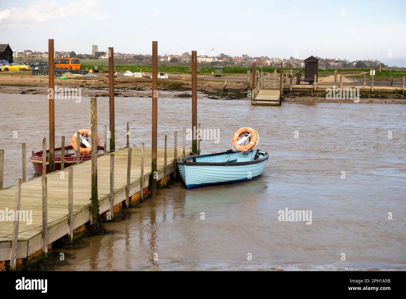 Wooden rowing boat tied to a wooden pier or jetty in the river in Walberswick in Suffolk Stock Photo
