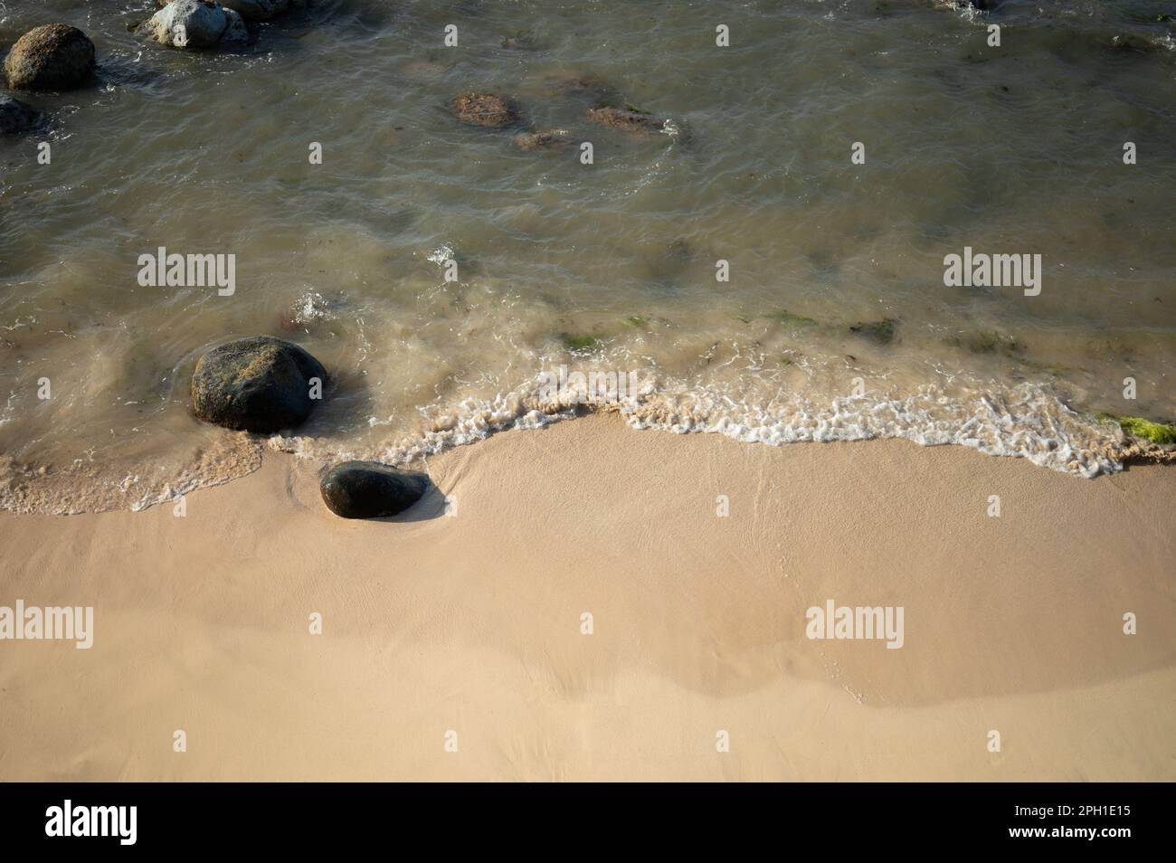 Sandy beach with stone peddle close up view on bright sunny day Stock Photo
