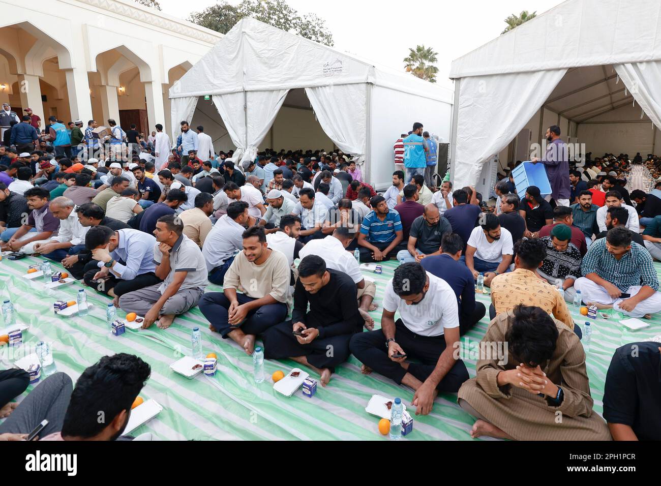 Dubai, UAE, 25th.March, 2023. Muslim people   in the Al Fahidi Historical District outside the Al Farooq Mosque in Dubai are waiting to break the daily Ramadan Kareem  fast with an evening meal on Saturday 25 03. 2023 © Juergen Hasenkopf / Alamy Live News Stock Photo