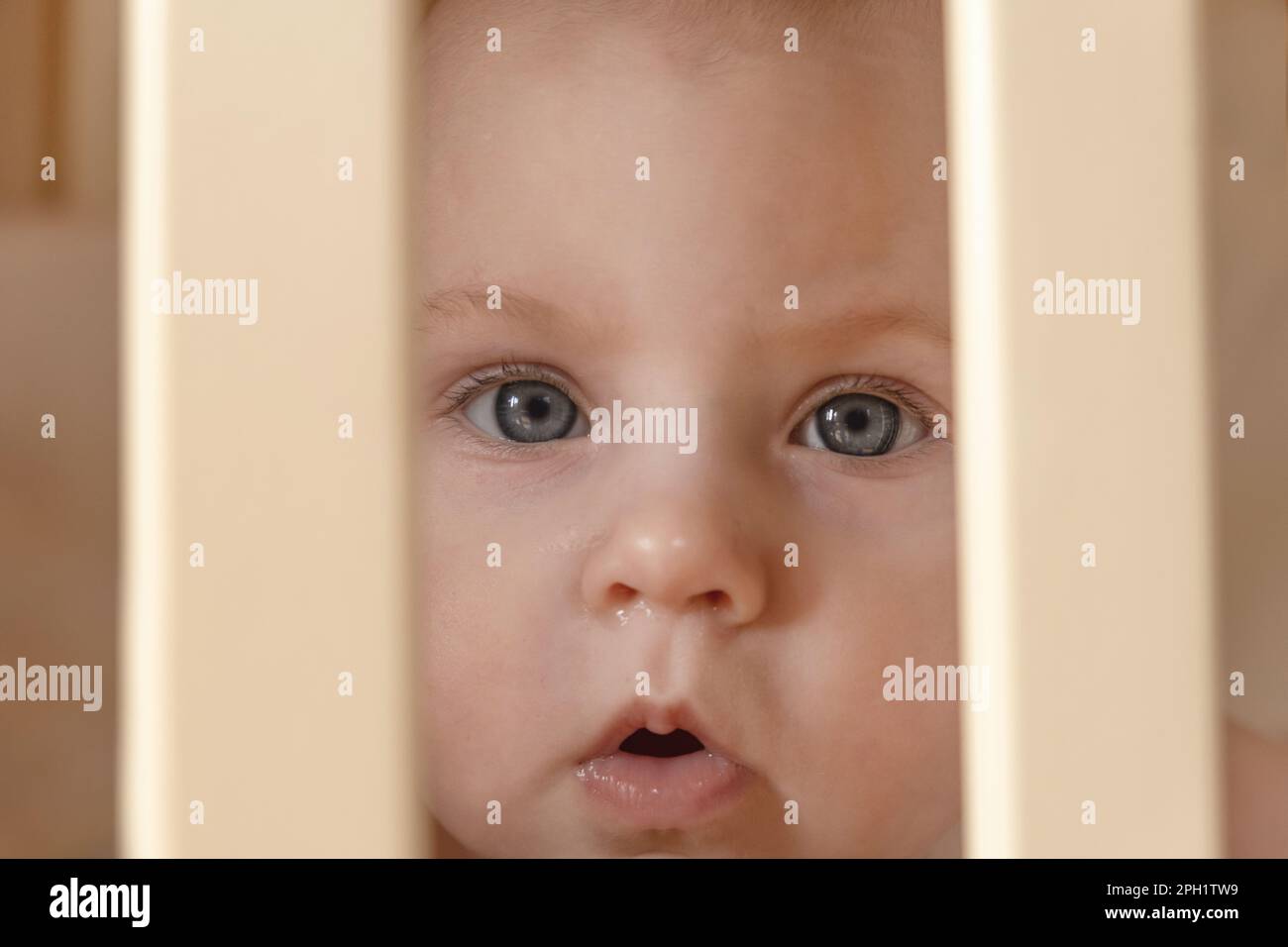 Closeup face of a crying cute baby in the crib at home. Little baby