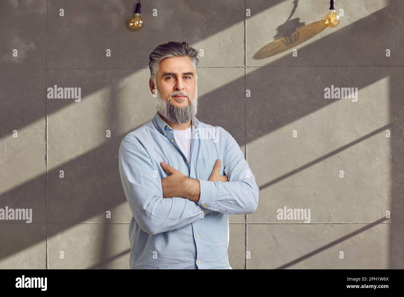 Portrait of middle aged bearded man standing with crossed arms Stock Photo