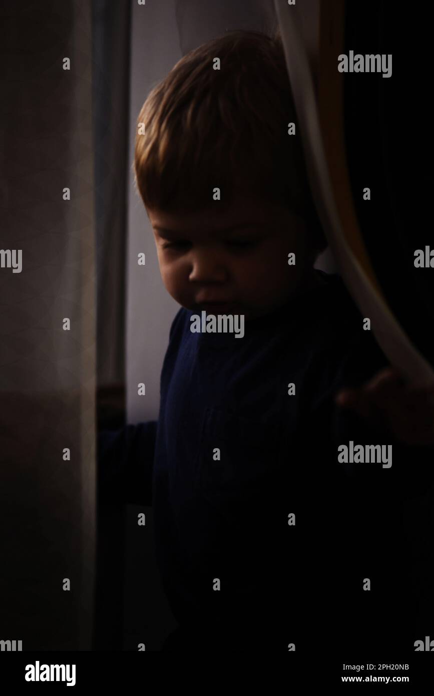 A two-year old boy near a window behind sheer curtains Stock Photo - Alamy