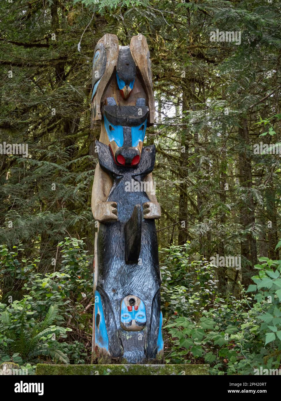 BC00689-00...BRITISH COLUMBIA - A first nations totem pole featuring a raven, bear, and orca located in the forest next to the Sunshine Coast Trail at Stock Photo