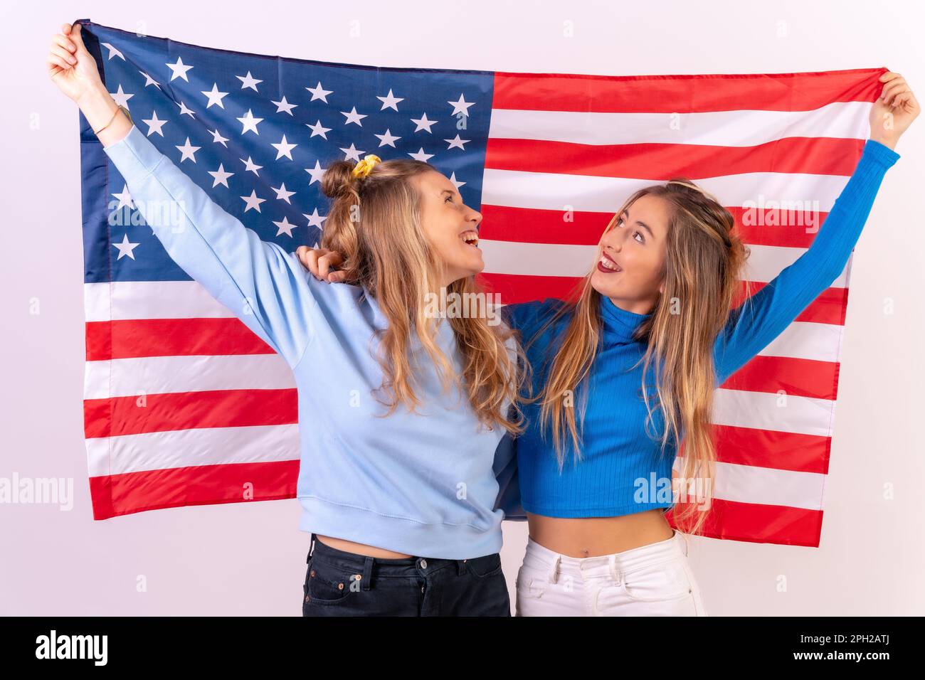 Two smiling females friends proudly displaying the American flag while ...