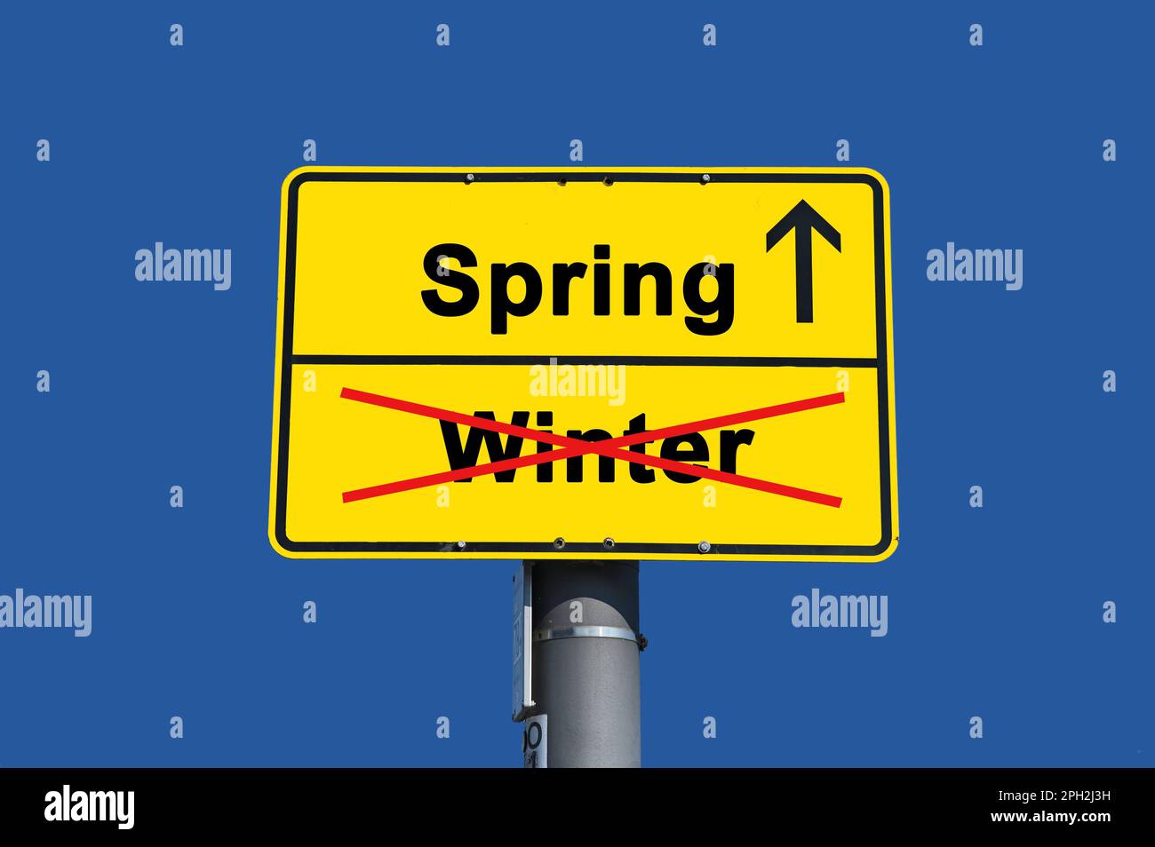 Yellow sign with black lettering. Below the word winter crossed out in red and above it the word spring with an arrow. Stock Photo