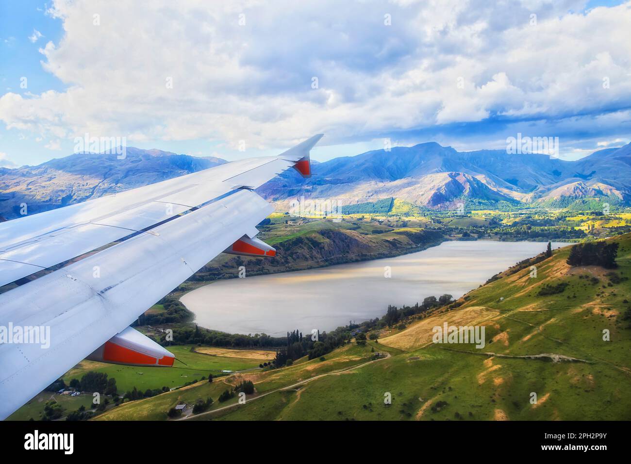 Passenger airplane jet engings wing over Lake Hayes around QUeenstown in New Zealand Stock Photo