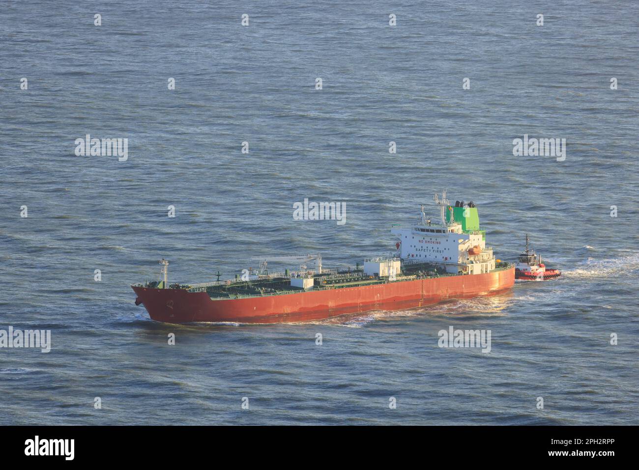Cargo Ship and Tugboat Navigate Calm Ocean Waters Entering Port Stock Photo