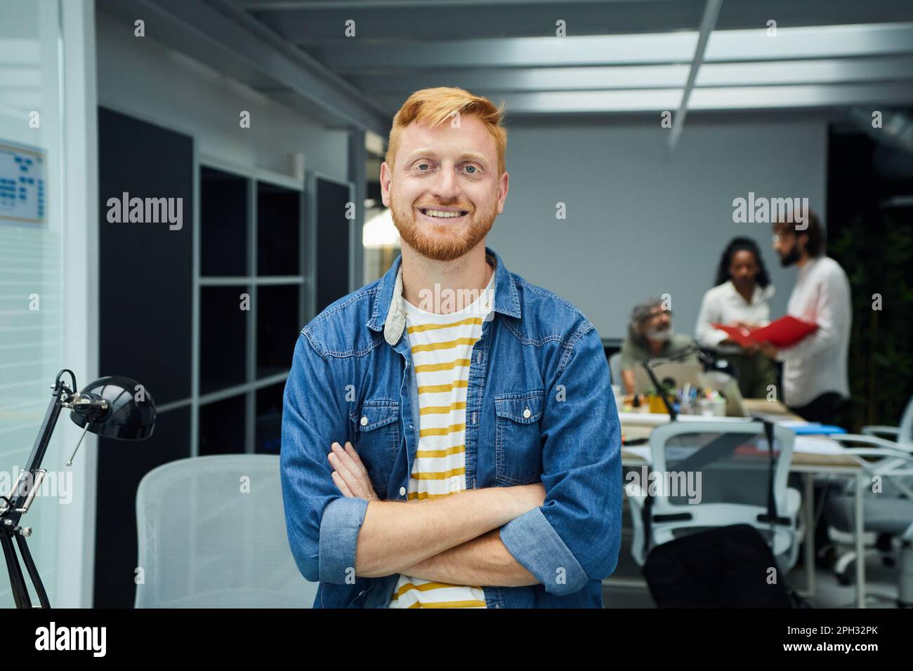 Young red-haired programmer or businessman in a modern office looking camera and smiles. Stock Photo