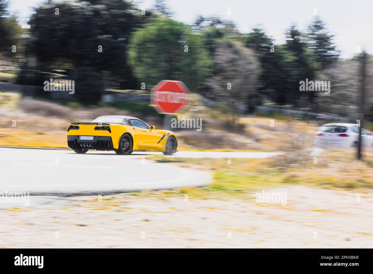 Yellow luxury sports car, driving at high speed on an urban road during the day, sweeping Stock