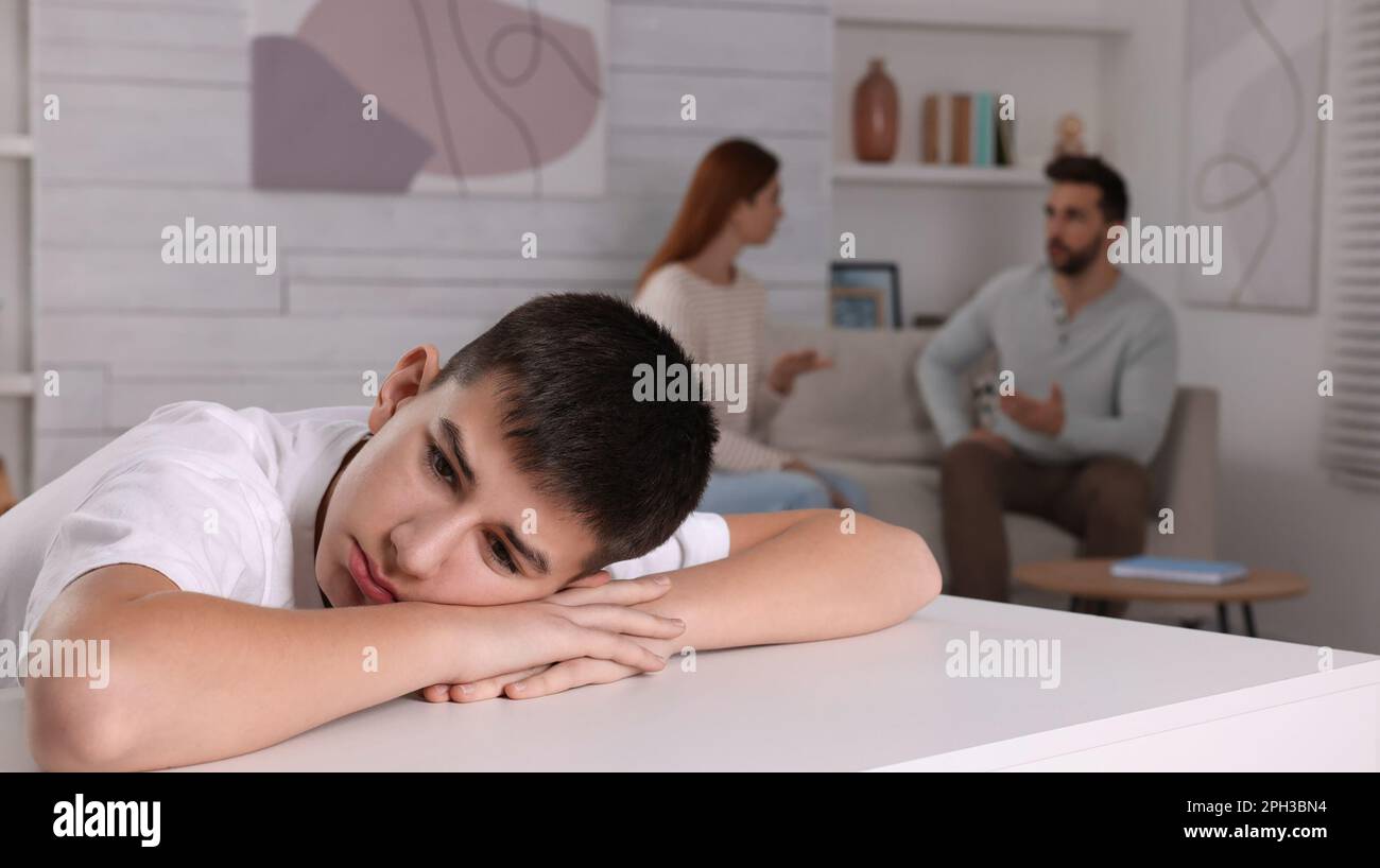 Couple arguing at home, focus on their unhappy teenage boy. Problems in family Stock Photo