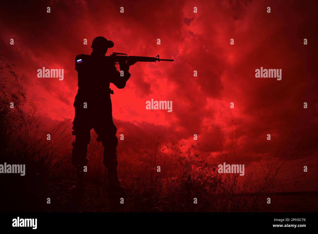 Russian invasion of Ukraine. Silhouette of armed soldier from Russia outdoors, toned in red Stock Photo