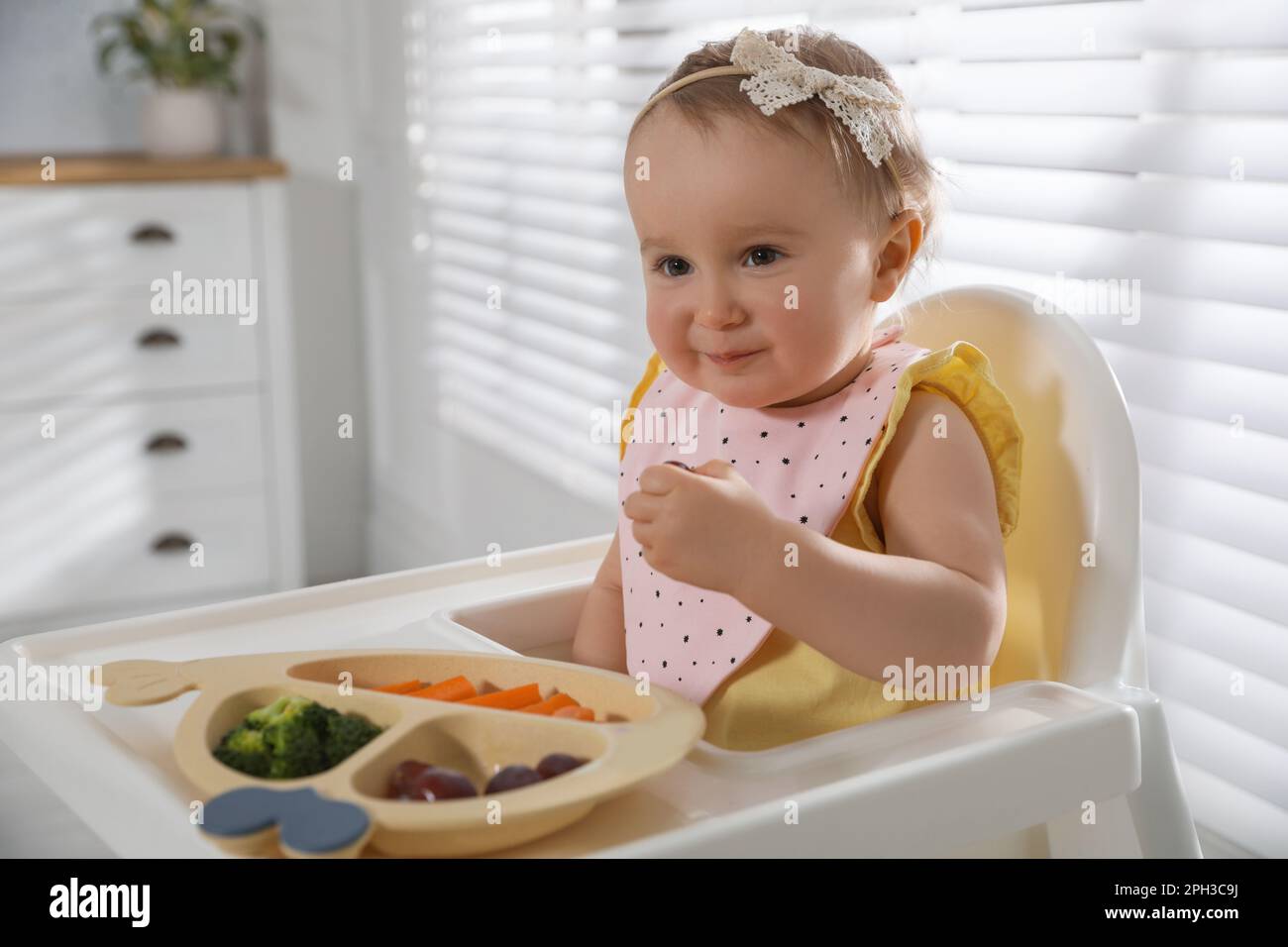 Cute little baby wearing bib while eating at home Stock Photo Alamy