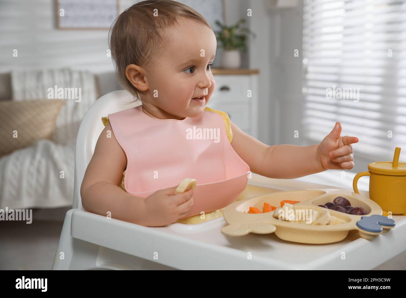 Cute little baby wearing bib while eating at home Stock Photo Alamy