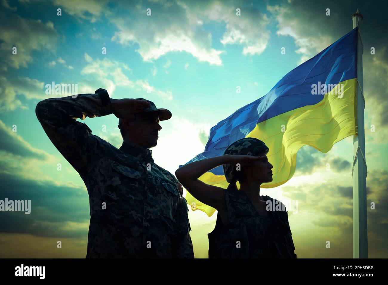 Stop war in Ukraine. Silhouette of soldiers saluting to Ukrainian flag outdoors Stock Photo