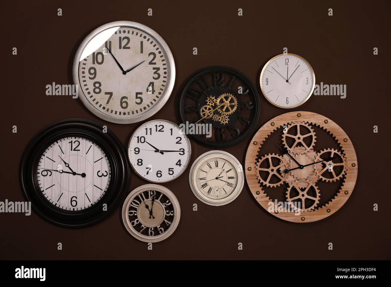 Collection of stylish clocks on brown wall Stock Photo - Alamy