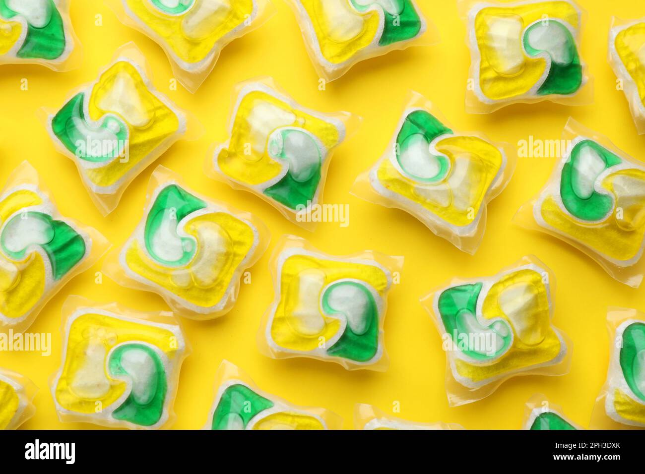 Many dishwasher detergent pods on yellow background, flat lay Stock