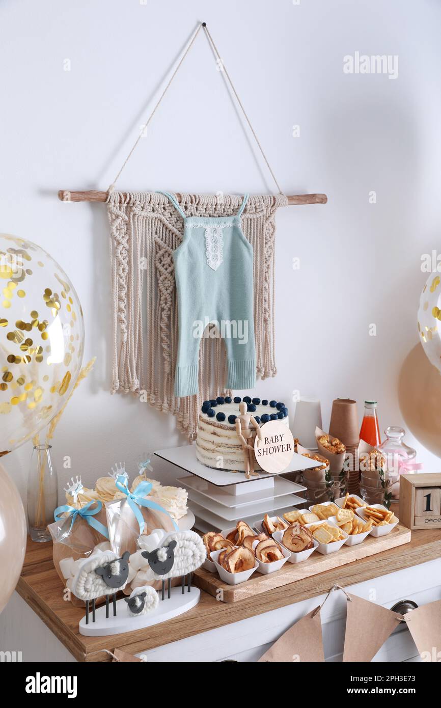 Baby shower party. Different delicious treats on white wooden chest of  drawers and decor near light wall Stock Photo - Alamy, image size:866x1390